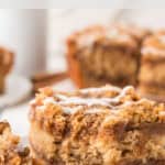 A close-up of a slice of cinnamon coffee cake with icing on top. The cake appears moist with visible cinnamon swirls. Text above reads An Old Fashioned Classic Cinnamon Coffee Cake.