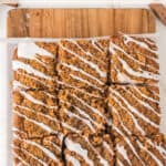 Sliced cinnamon coffee cake with white icing drizzle on parchment paper and a wooden cutting board, with the text Cinnamon Coffee Cake above.