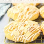 Golden, crescent-shaped pastries with white icing and almond slices sit on a cooling rack. Text above reads “How to Make Classic Butterhorns.” Website theurbankitten.com is at the bottom.