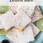 A blue plate with powdered sugar-dusted lemon bars, with lemon slices for garnish. Text reads Sweet & Tart Lemon Bars and by theurbankitten.com at the bottom.