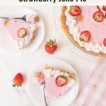 Overhead view of a no-bake strawberry Jello pie topped with whipped cream and strawberry slices, with two slices served on plates, forks, and fresh strawberries on a white surface.