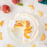 Overhead view of a pie with whipped topping and peach slices, surrounded by fresh peaches and peach slices on a white surface. Text reads Retro Jello Pie Peaches & Cream with theurbankitten.com at the bottom.