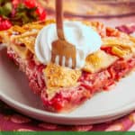 A slice of strawberry rhubarb pie topped with whipped cream is on a plate, with a fork in the pie. Fresh berries are visible in the background. Text at the bottom reads, “Strawberry Rhubarb Pie by theurbankitten.com.”.